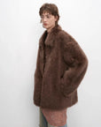 Woman modeling the cocoa brown Toscana shearling coat, side view