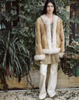 Model wearing Casual Gene Yellow Apricot fur coat in a garden setting