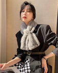 Woman styling a silver gray mink flower scarf in natural light