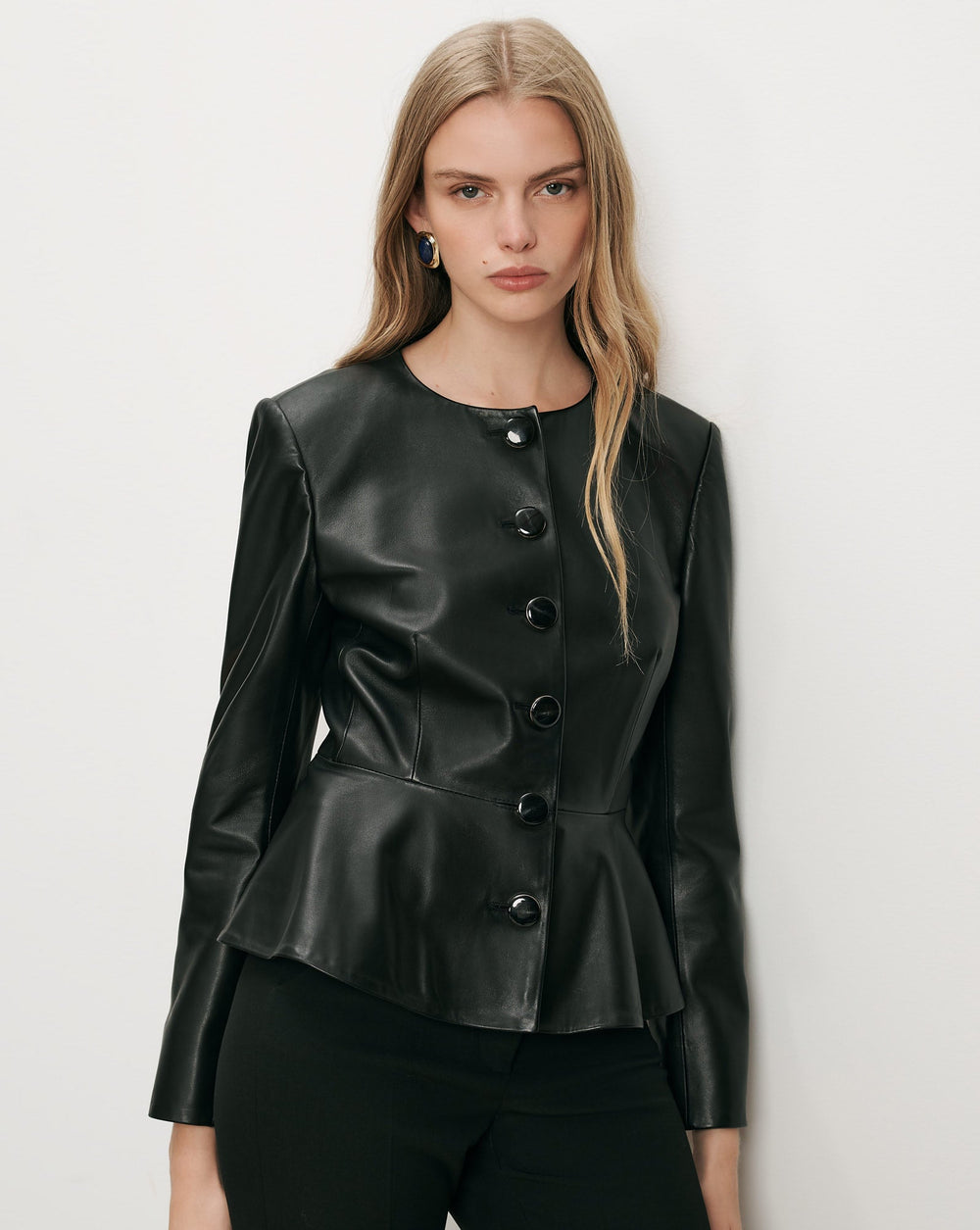 Black round-neck jacket with large round buttons, fitted waist and a visibly flared lower hem.