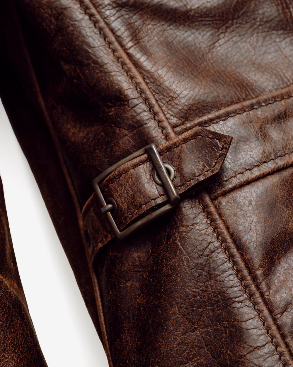 Brown Schott 543 leather close-up showing surface variation, stitched panels and an adjustment tab.