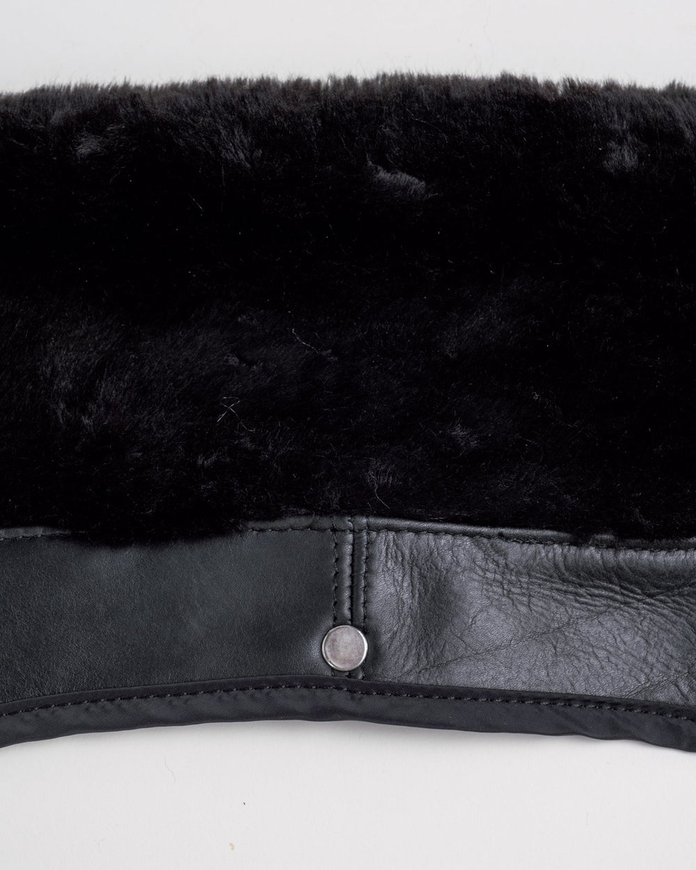 Underside of a black removable collar with backing and a metal snap.