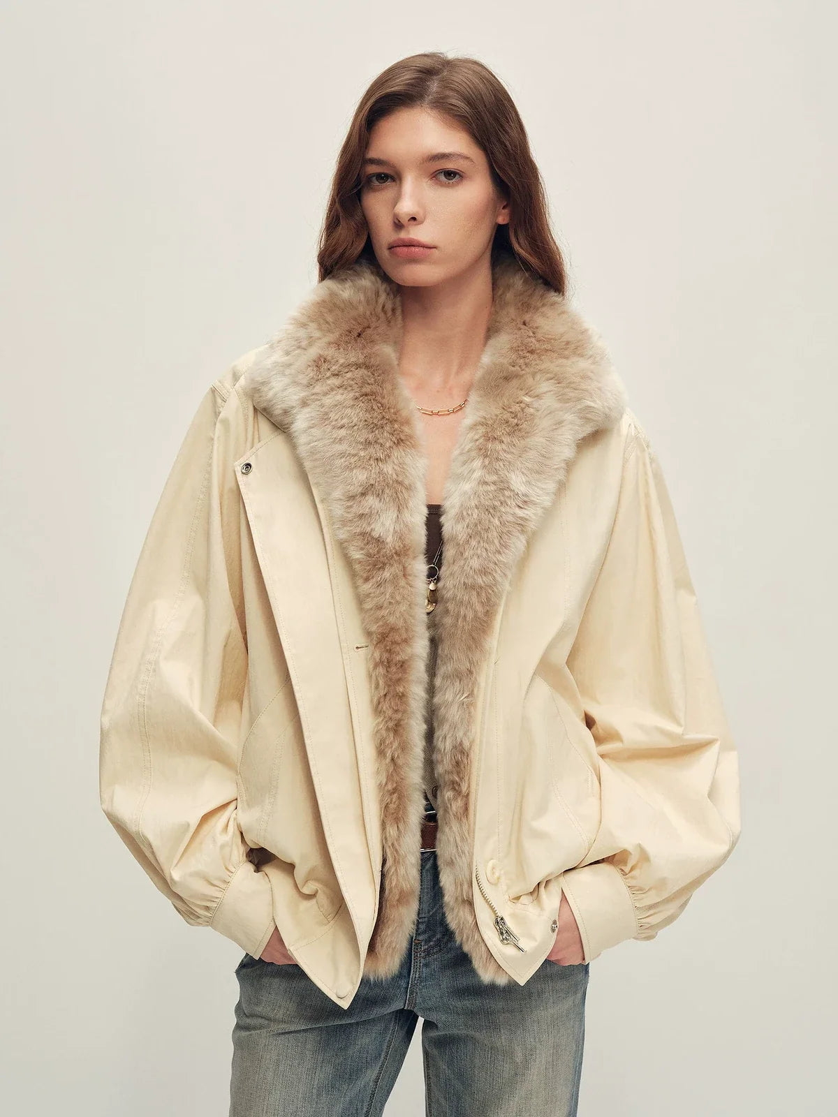 Real model wearing beige-gray short bomber with plush Merino shearling collar over a dark top and light jeans