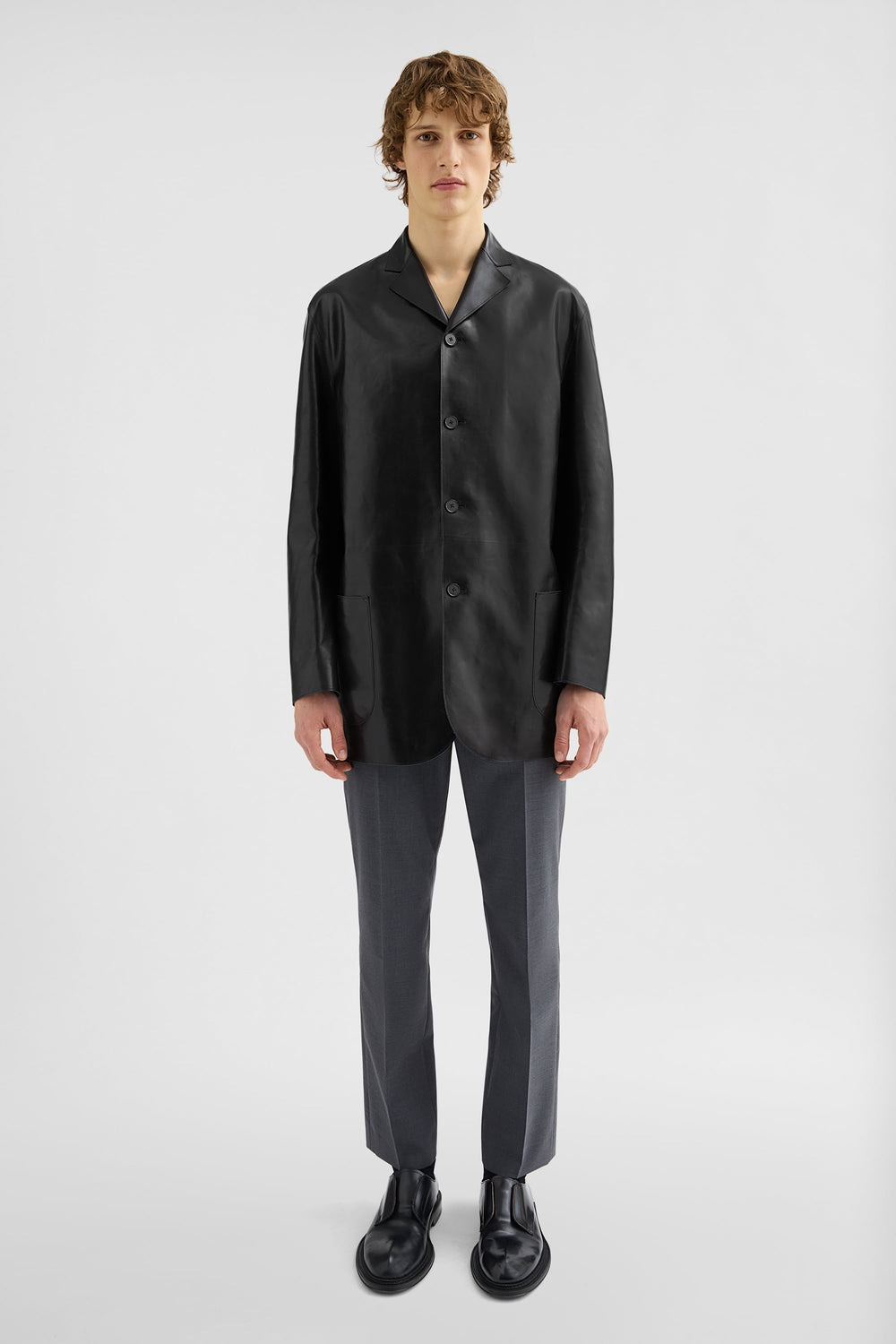 Front of black Jil Sander button-front jacket with lapels, patch pockets and rounded lower corners