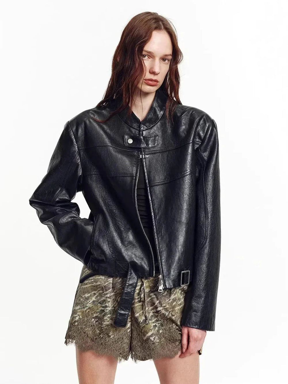 Woman wearing a black leather jacket with a light underlayer and dark trousers