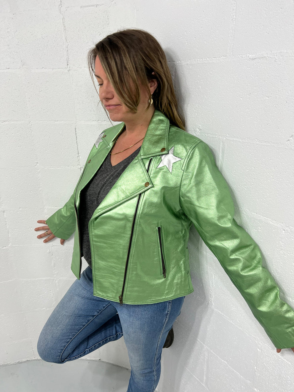 Green reflective zip-front biker jacket shown from the front/side with shiny sleeves and shoulders and a star near one shoulder