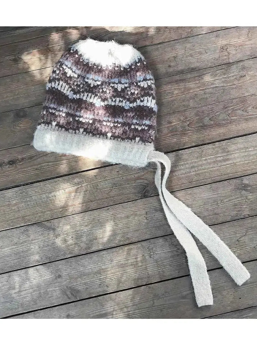 Women's khaki jacquard wool knit hat with tassel on rustic wood