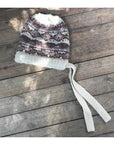 Women's khaki jacquard wool knit hat with tassel on rustic wood