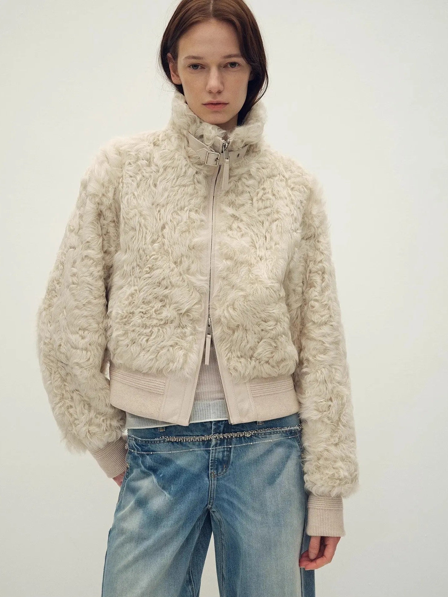 Model wearing the Curly Story light khaki sheep curly shearling bomber jacket, close front view