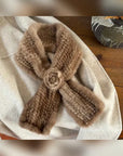 Woman styling a silver gray mink flower scarf by a window