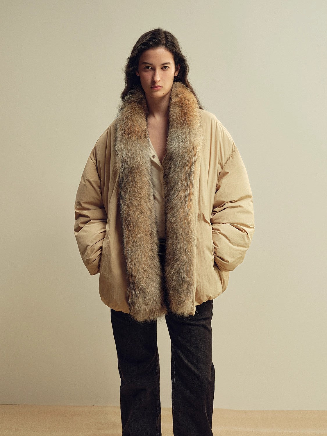 Padded beige parka with generous fur trim and insulated volume